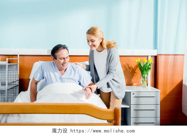 帮助丈夫从医院的病床上站起来的女人医生看诊病人